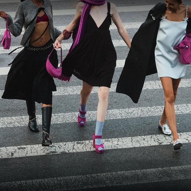 Two women walking on a city street, each carrying an animal print shoulder bag with long strap.