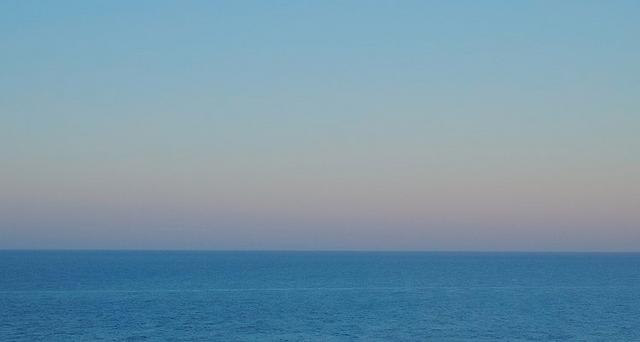 Calm ocean horizon at dusk with gradient sky transitioning from blue to soft pink tones.