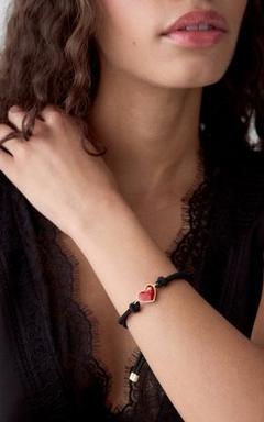 Woman wearing a red heart-shaped bracelet with black cord on her wrist.