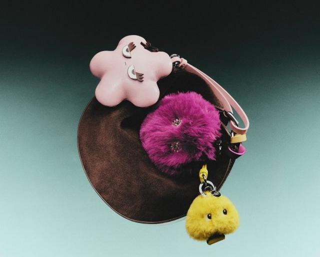 Keychain with pink flower charm, magenta fur pom-pom, and yellow fuzzy chick charm attached to ring.