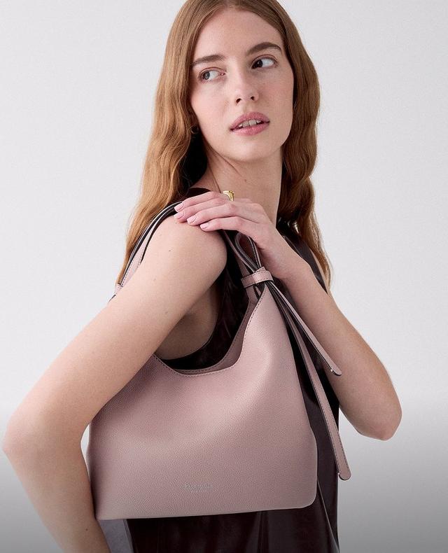 Woman wearing a mauve hobo shoulder bag with brown leather straps and gold-tone hardware.