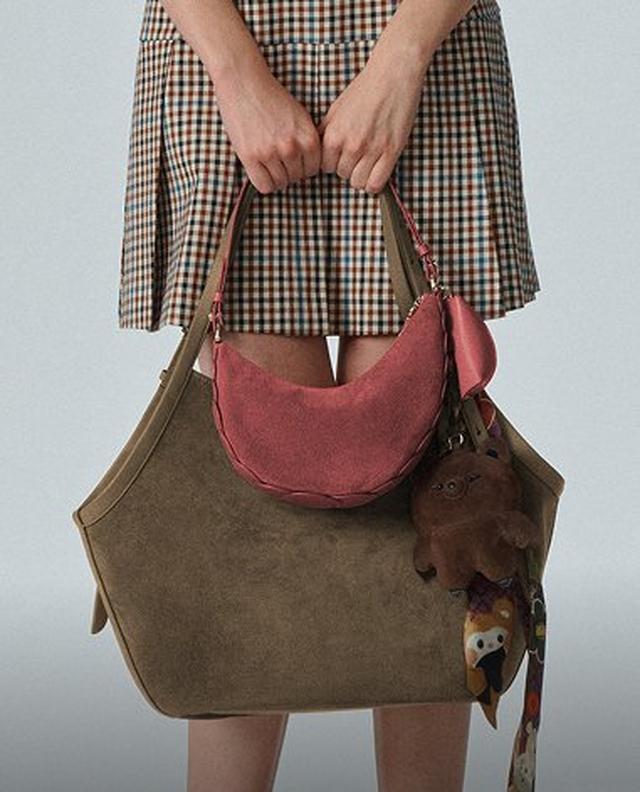 Woman wearing a mauve hobo shoulder bag with brown leather straps and gold-tone hardware.