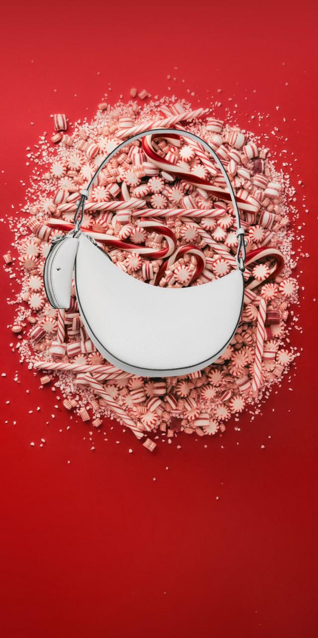 White crescent moon ornament hanging over peppermint candies and candy canes spilling from a basket.