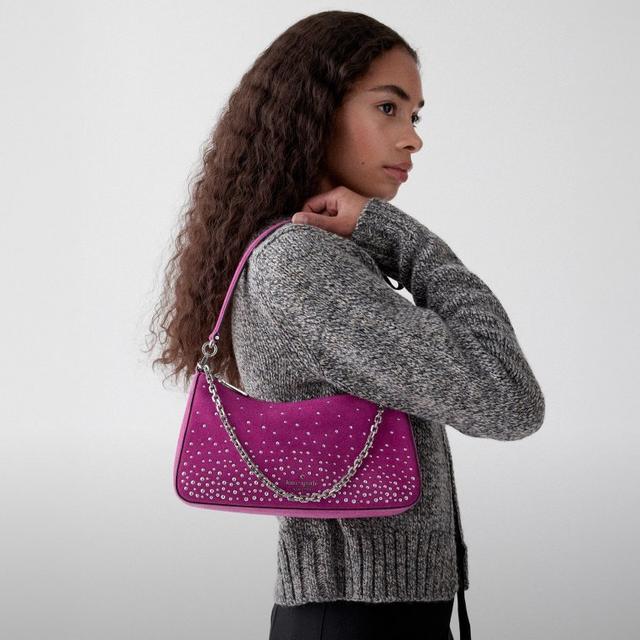 Model wearing gray sweater carries magenta Kate Spade shoulder bag with studded embellishment and chain.