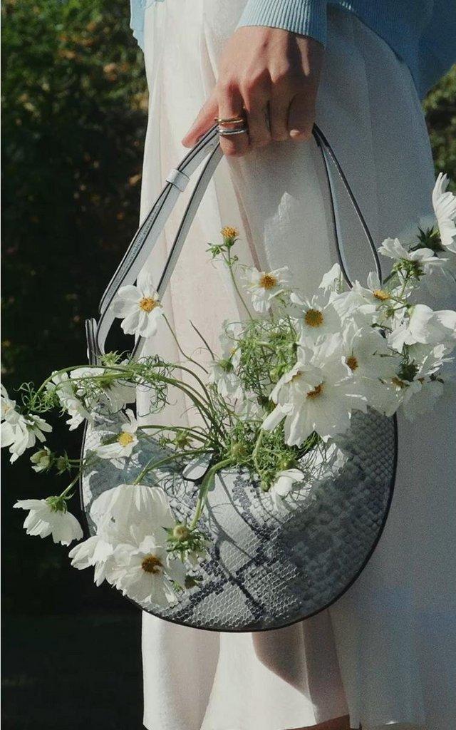a woman holding a purse with flowers in it