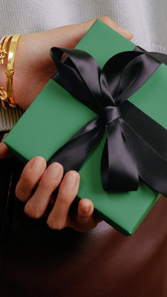 a woman holding a green box with a bow on it