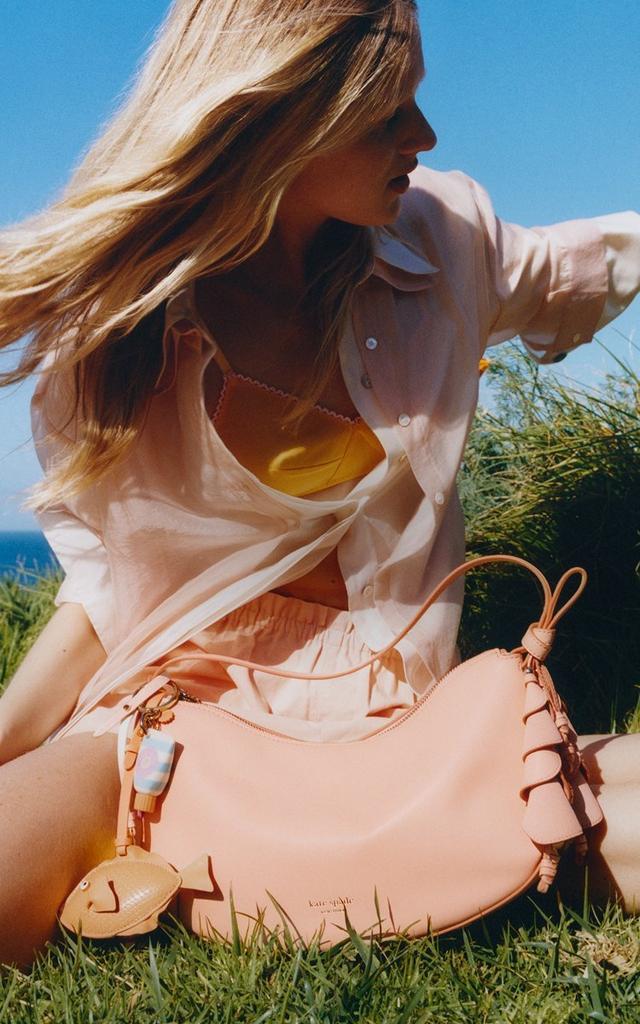 two women are jumping in the spring air together and smiling wearing the kate spade duo bag