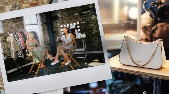 Model being photographed in a brown outfit at a studio photoshoot with Kate Spade handbag displayed.