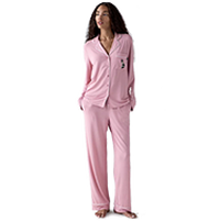 Woman wearing a pink long-sleeved pajama set with button-up top and matching pants.