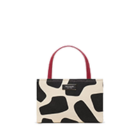Small structured handbag with black and white cow print pattern and burgundy handles.