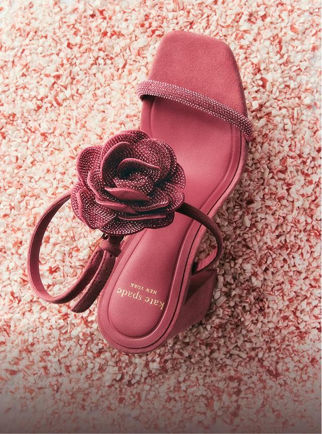 Kate Spade pink slide sandals with decorative flower embellishment on confetti surface.